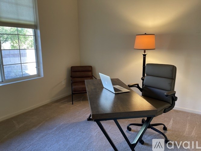 A room with a table, a laptop, a chair and a lamp.
