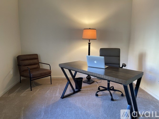 A room with a desk, chair, and lamp.