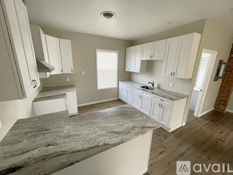 A kitchen with white cabinets and a marble countertop.