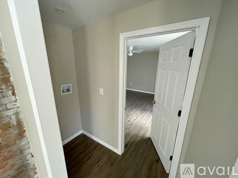 A room with a white door and a brick wall.