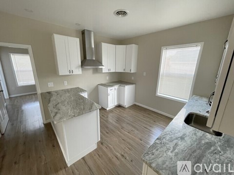 A kitchen with white cabinets and a marble countertop is available.