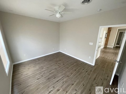 A room with a ceiling fan and wooden flooring.