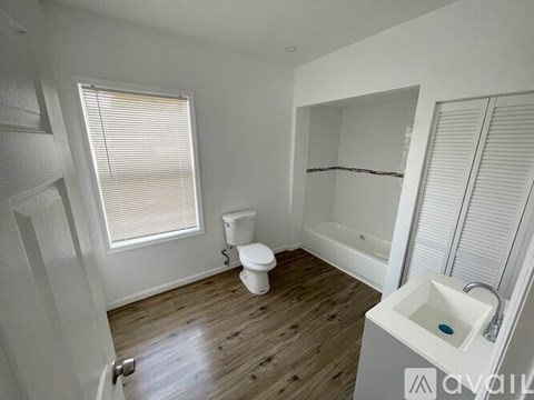 A white bathroom with a toilet, sink, and shower.