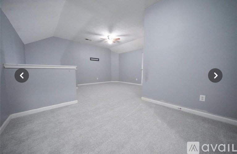 A spacious room with a carpeted floor and a white ceiling.