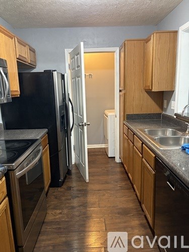 A kitchen with wooden cabinets and a black fridge.