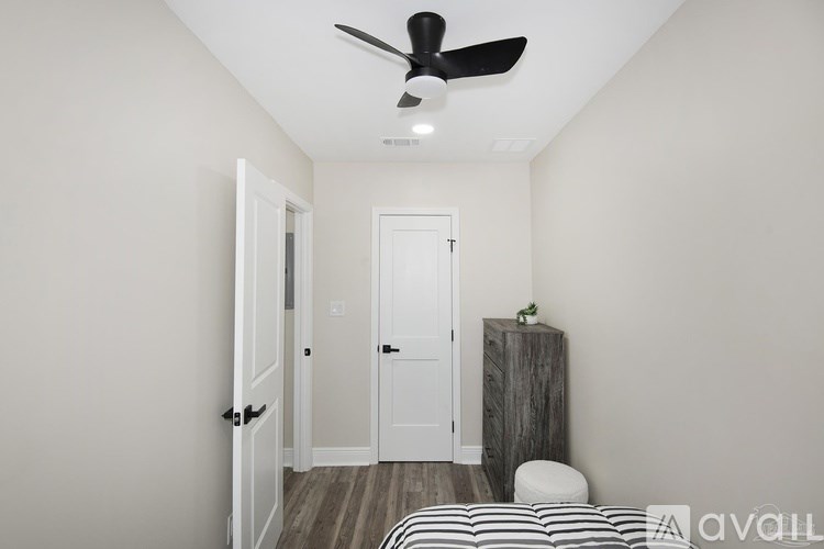 A room with a ceiling fan and a bed with a striped comforter.