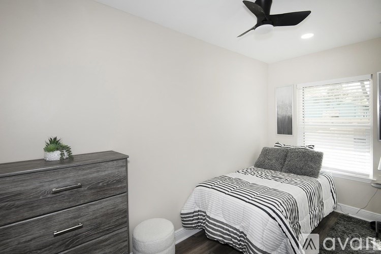 A bedroom with a bed, dresser, and ceiling fan.