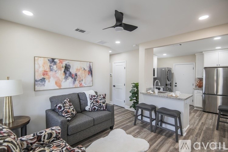 A living room with a grey couch and a painting on the wall.