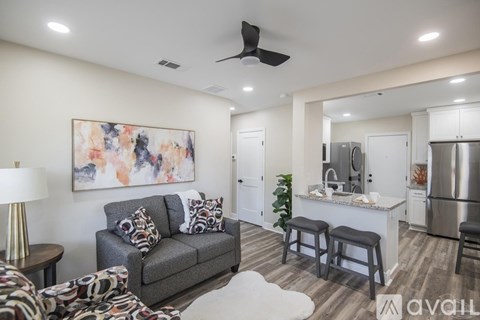 A living room with a grey couch and a painting on the wall.
