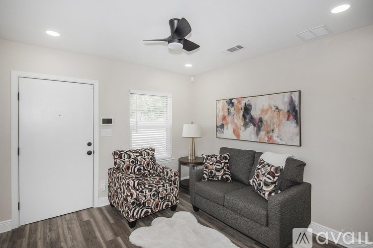 A living room with a grey couch, a patterned chair, and a painting on the wall.