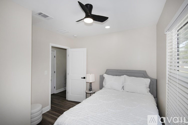 A bedroom with a bed, a ceiling fan, and a lamp.