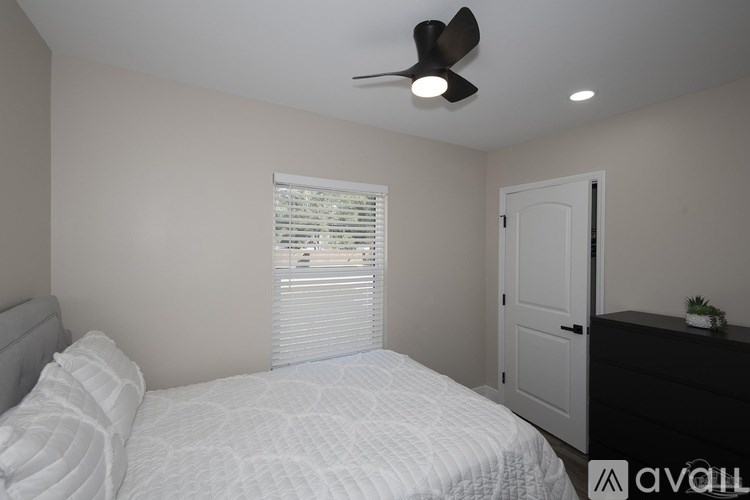 A bedroom with a bed, dresser, and window with blinds.
