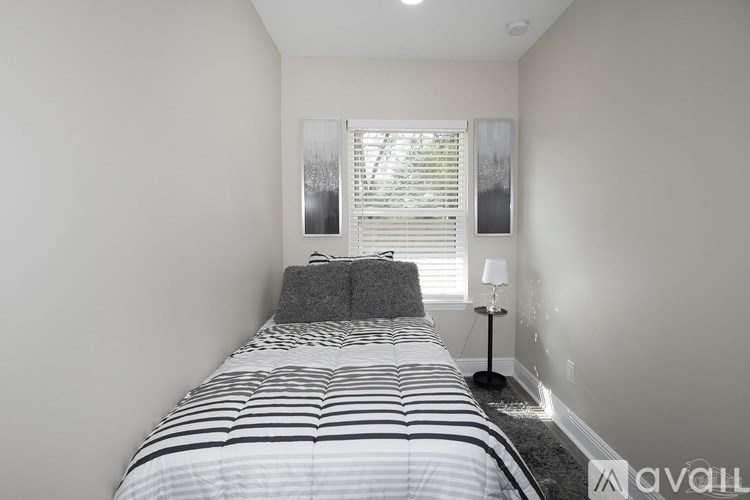 A bedroom with a bed, nightstand, and window.