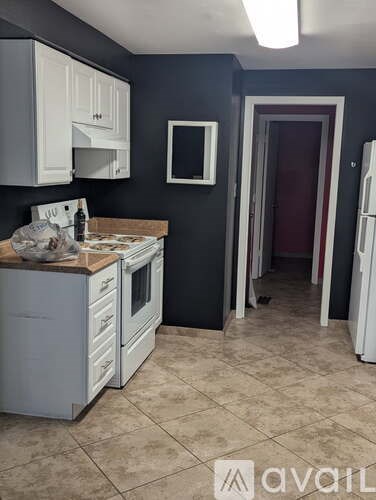 A kitchen with white appliances and cabinets against a dark wall.