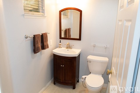 A bathroom with a toilet, sink, and mirror.