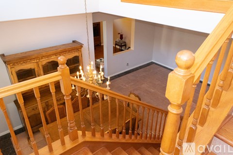 A wooden staircase with a chandelier hanging from the ceiling.