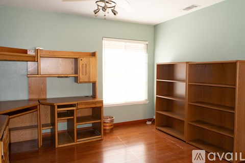 A room with a large wooden bookshelf and a desk with a chair.