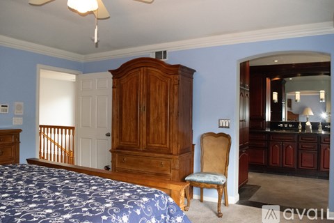 A bedroom with a large bed and a wooden armoire.