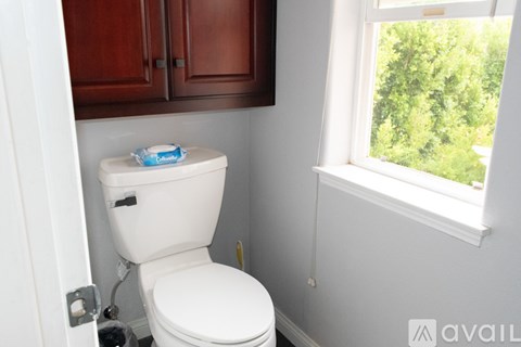 A white toilet in a small bathroom with a window.