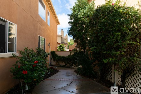 A garden pathway leads to a building with a fence and a gate.
