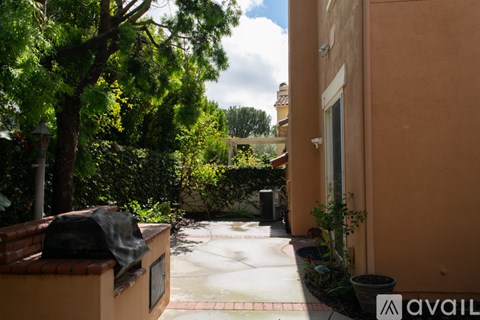 A sunny day in a residential area with a house and trees.