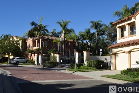 A white car is parked on the street in front of a house with a gate.