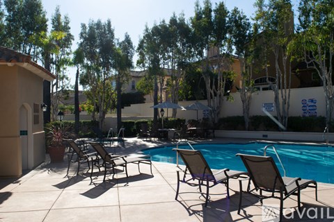 A pool surrounded by trees and chairs.