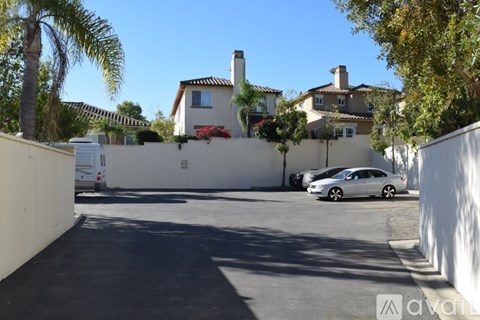 A white car is parked in a driveway in front of a house.