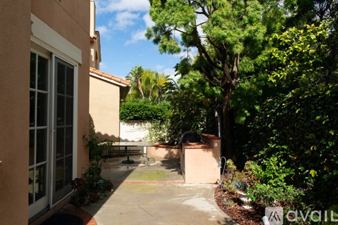 A patio area with a table and chairs surrounded by greenery.