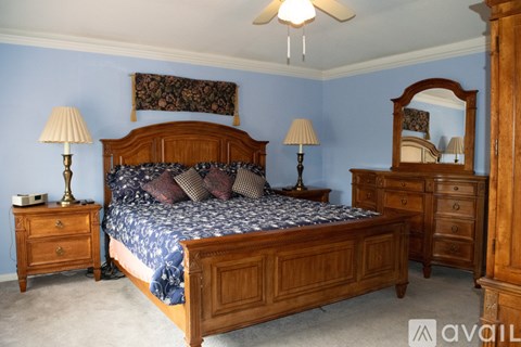 A bedroom with a large bed, a dresser, and a mirror.