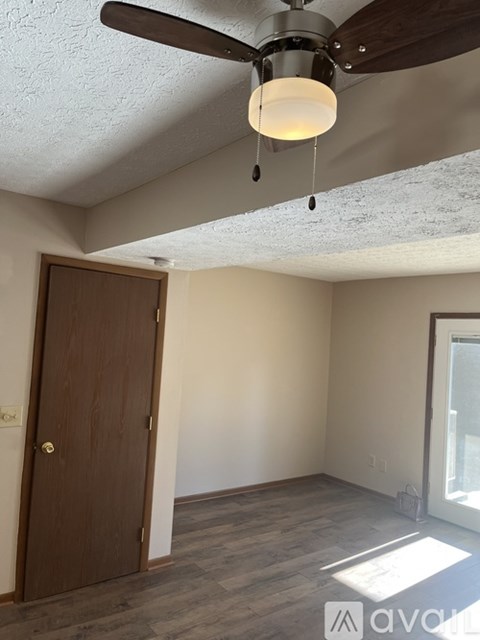 A room with a ceiling fan and a door.