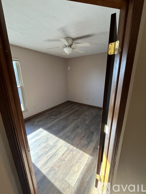 A room with a ceiling fan and wooden flooring.