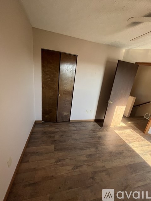 A room with wooden flooring and a brown door.