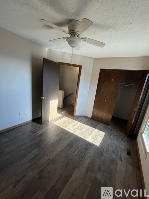 A room with a ceiling fan and wooden flooring.