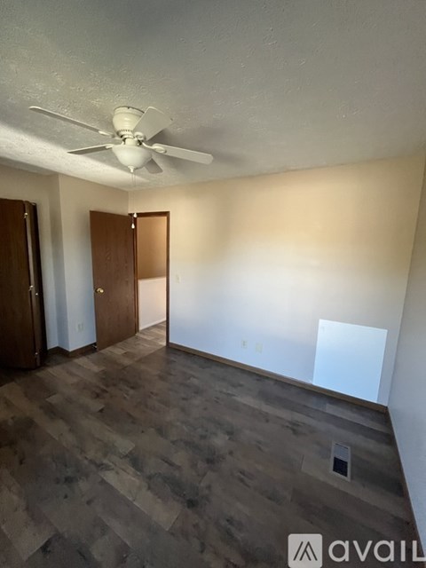 A room with a ceiling fan and wooden flooring.