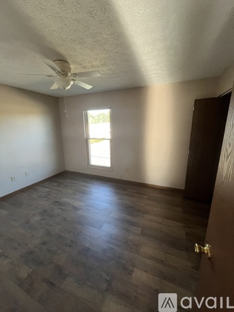 A room with a ceiling fan and a window letting in sunlight.