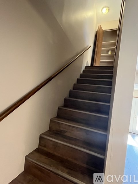A staircase with a wooden handrail and steps leading up to a door.