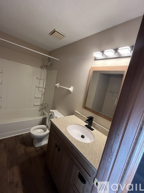 A bathroom with a toilet, sink, and mirror.