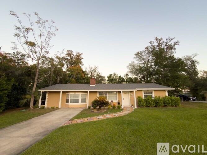 A house with a driveway and a tree in front of it.