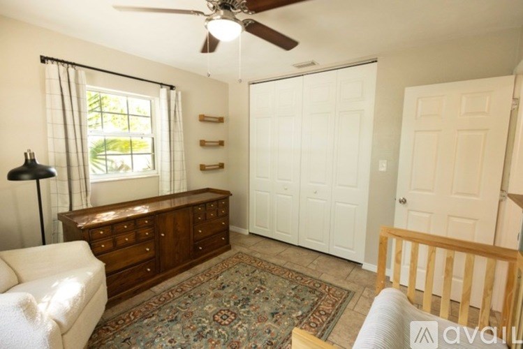 A room with a ceiling fan, a couch, a rug, and a window.