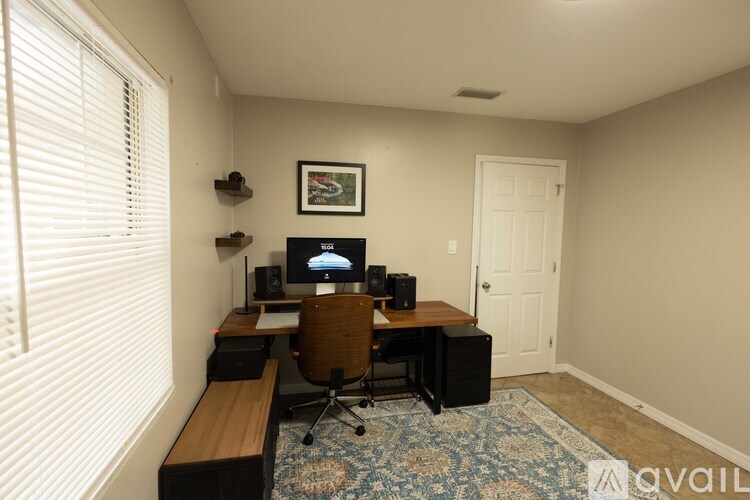 A room with a desk, chair, and a computer monitor.
