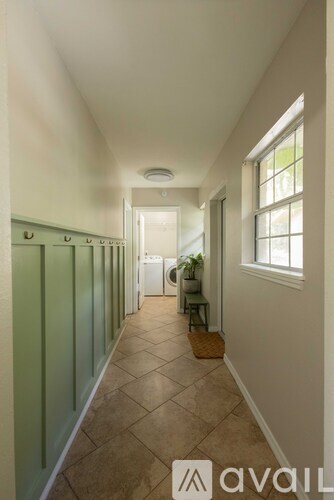 A hallway with green doors and a basket on the floor.