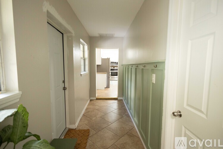 A hallway with a green door and a brown doormat.