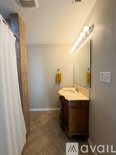 A bathroom with a toilet, sink, mirror, and a shower curtain.