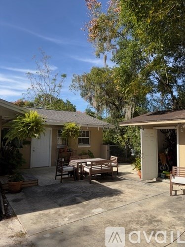 A patio with a table and chairs is surrounded by trees.