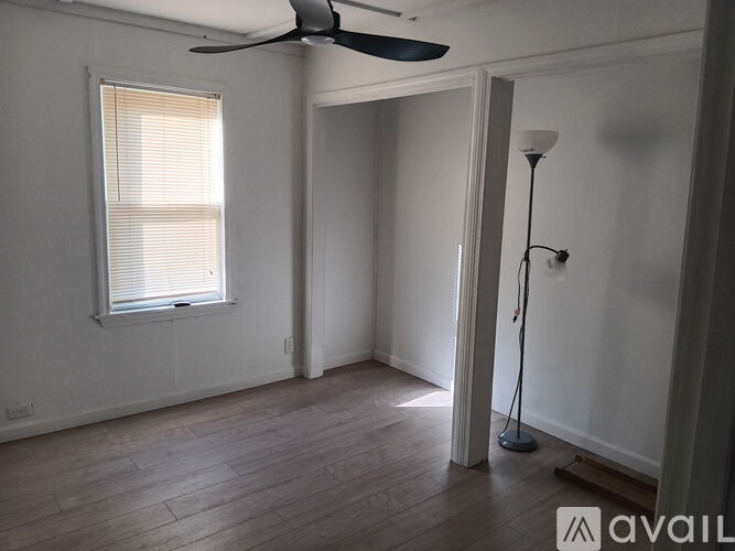 A room with a fan, a window with blinds, and a floor lamp.