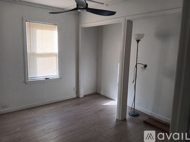 A room with a fan, a window with blinds, and a floor lamp.