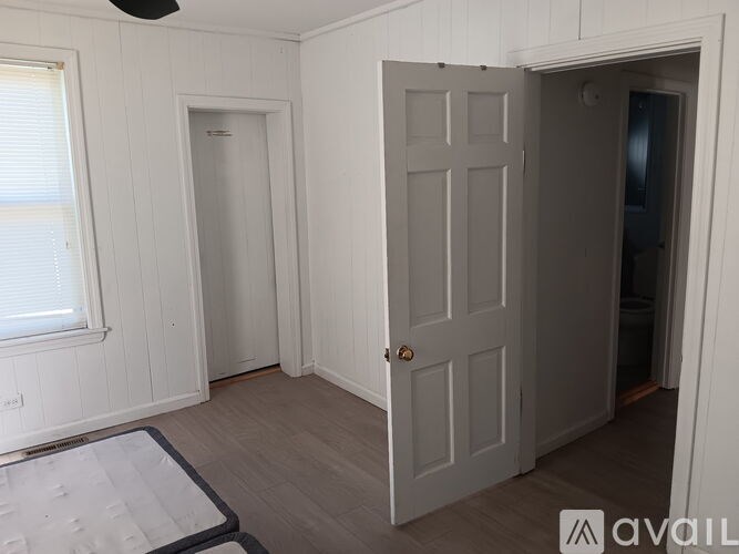 A room with a mattress on the floor and a door on the right.