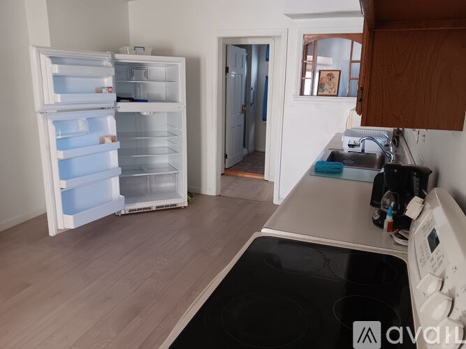 A kitchen with a white fridge, black stove, and wooden cabinets.