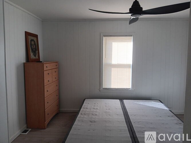 A bedroom with a bed, dresser, and window.